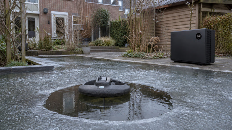 Oase IceFree Thermo 200 in een wak en AquaForte Mr. Silence warmtepomp naast een bevroren koivijver