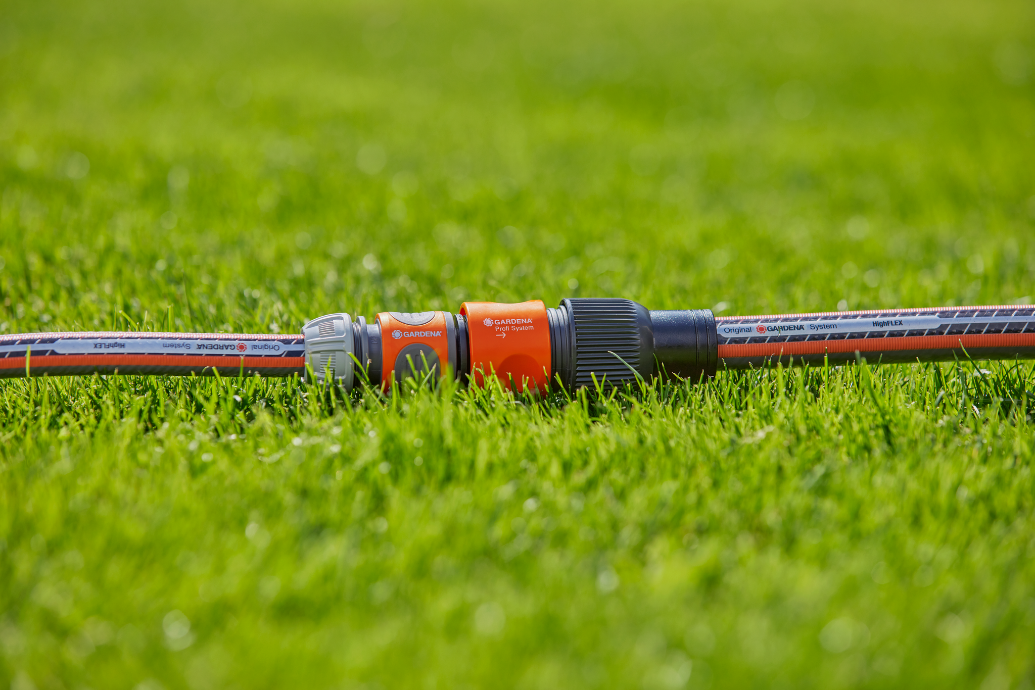 Close-up of a Gardena garden hose connector on a lawn.