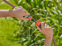 Two hands connecting Gardena hose fittings in a garden setting., miniatuur 3