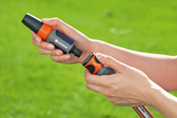 A person connecting a Gardena hose nozzle to a garden hose in a grassy area., miniatuur 3