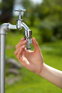A hand attaching a Gardena hose connector to a garden tap outdoors., miniatuur 4