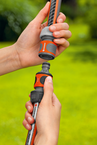 Hands connecting Gardena hose fittings in a garden setting., miniatuur 3
