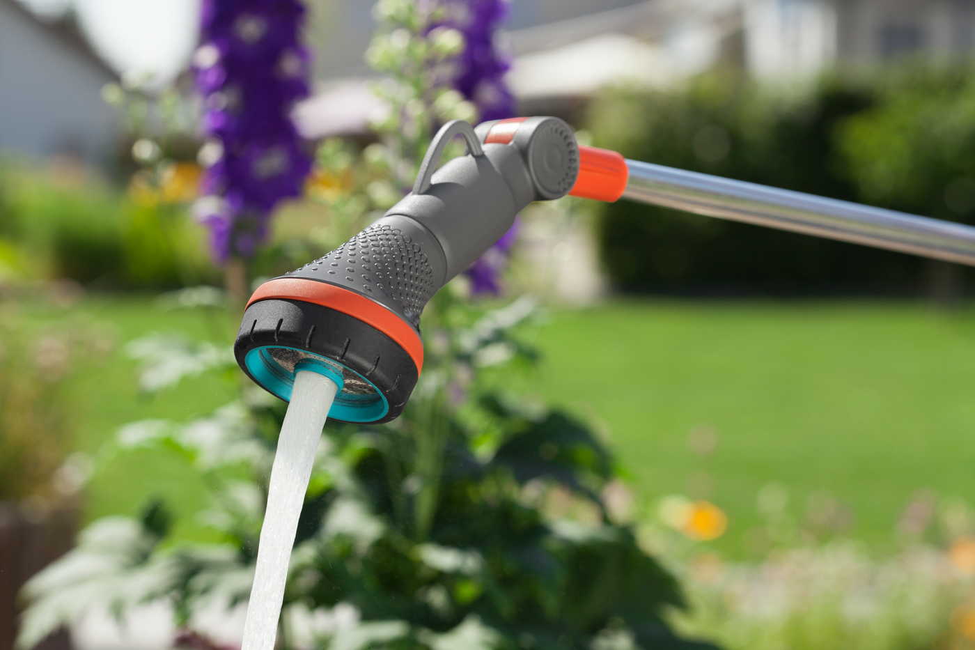 A garden hose nozzle spraying water in a garden setting.