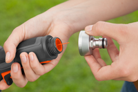 A person holding a garden hose nozzle and a connector, preparing to attach them., miniatuur 6