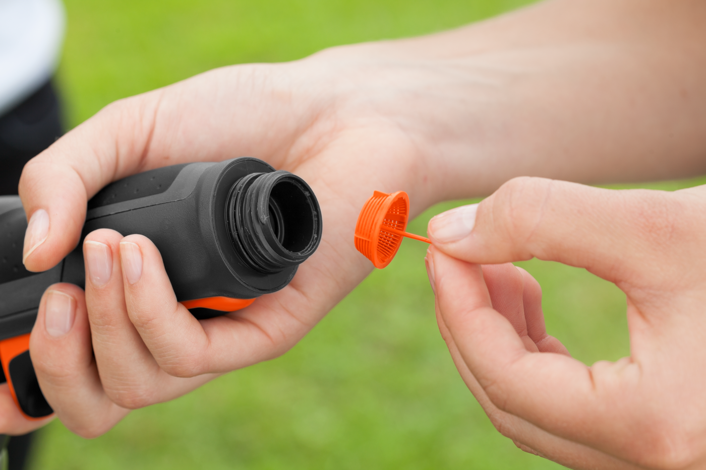 A person opening the cap of a garden spray bottle, preparing for use.