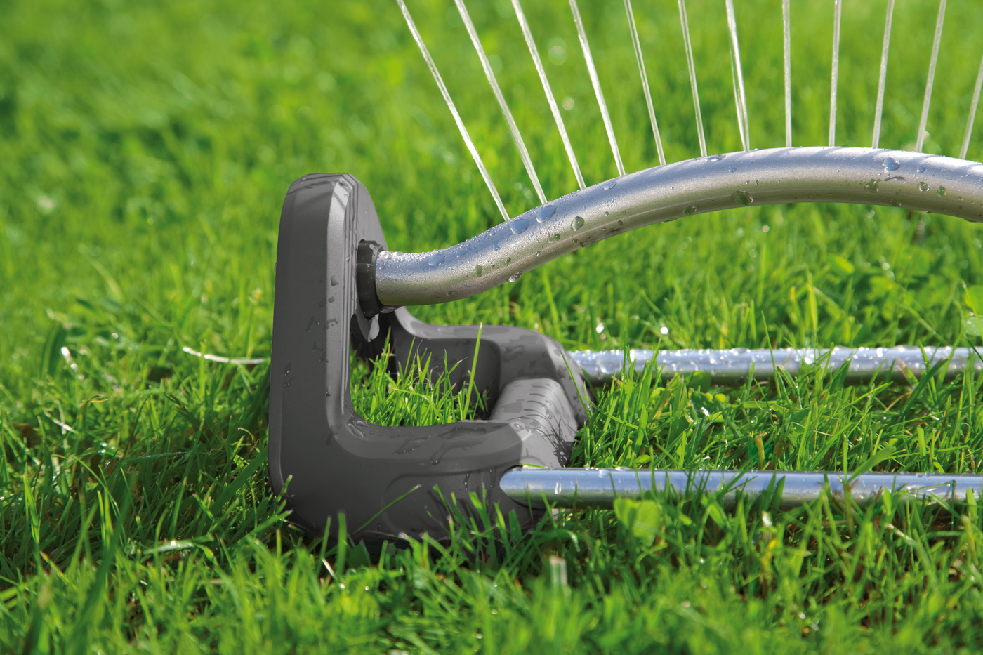 A garden sprinkler watering grass with water droplets visible on the sprinkler.