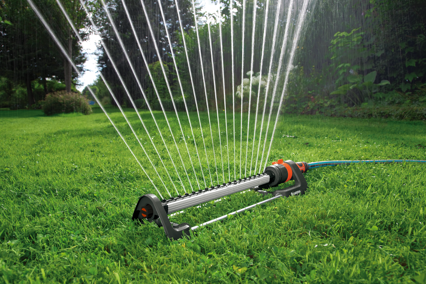 Oscillating sprinkler watering a lush green lawn in a garden setting.