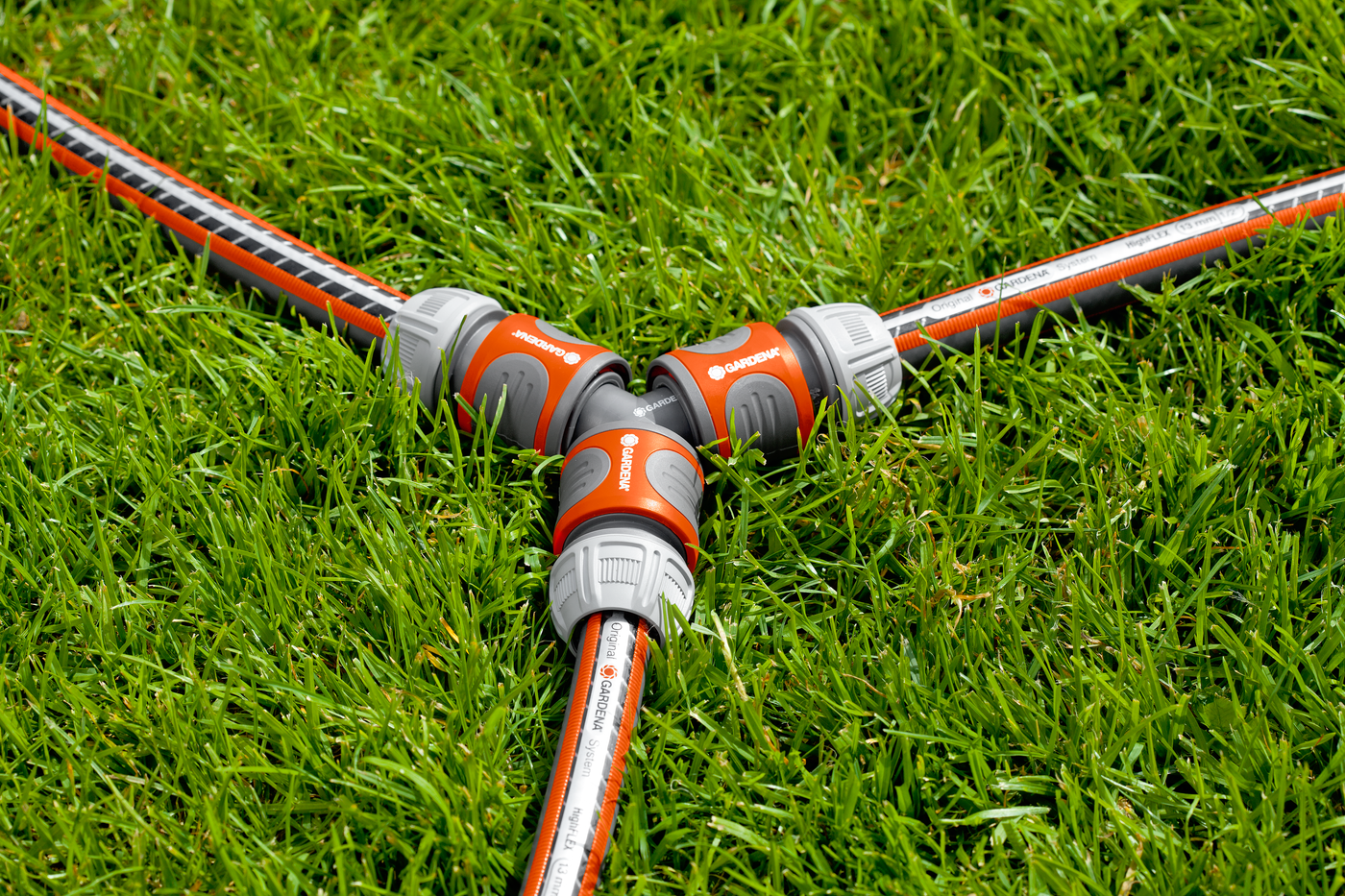 Gardena hose connectors forming a Y-shape on a grassy lawn.