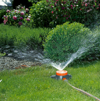A garden sprinkler watering a lush green lawn surrounded by bushes and flowers., miniatuur 2