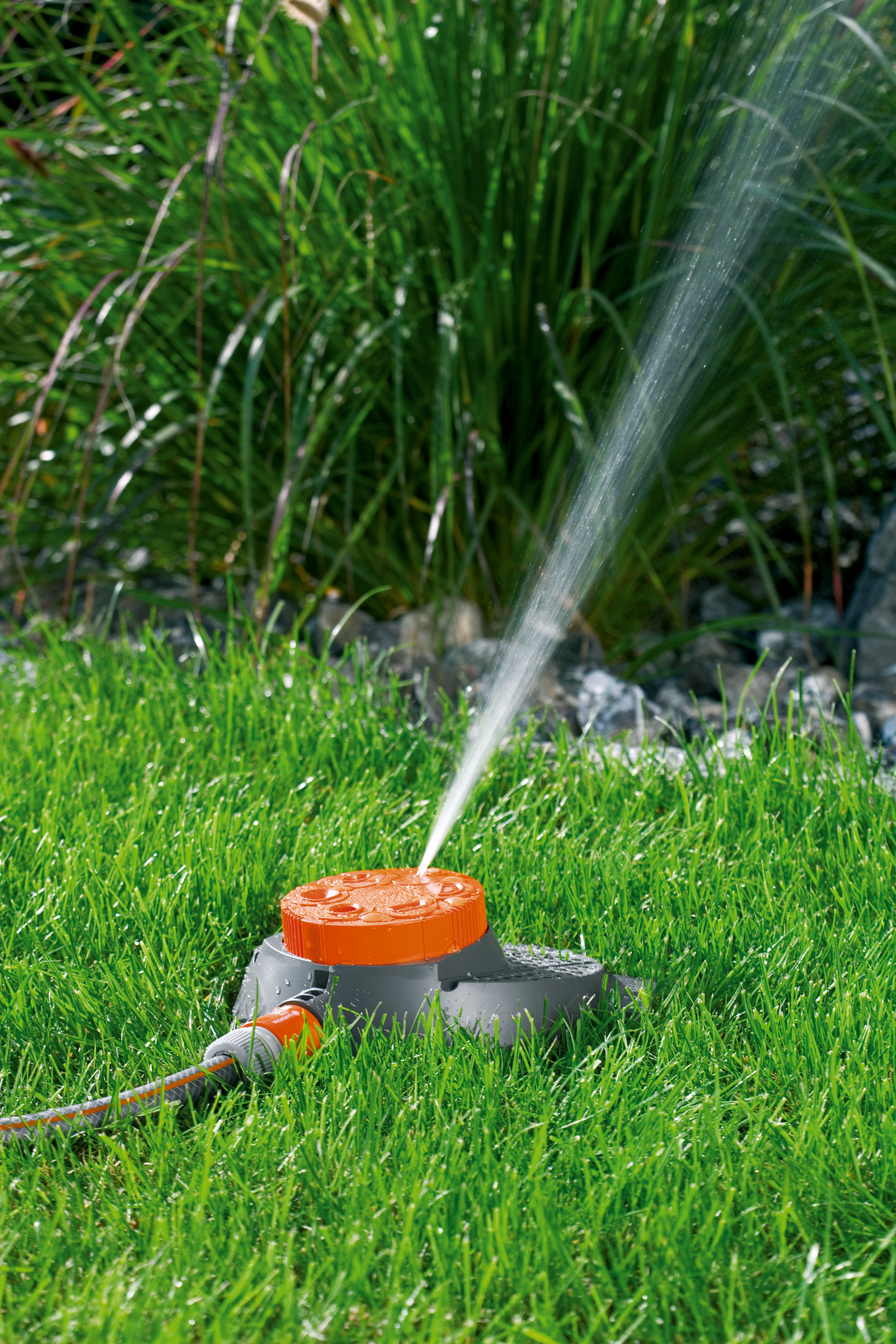 A garden sprinkler watering grass with a spray of water.