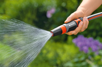 A person using a Gardena garden hose nozzle to spray water in a garden., miniatuur 4