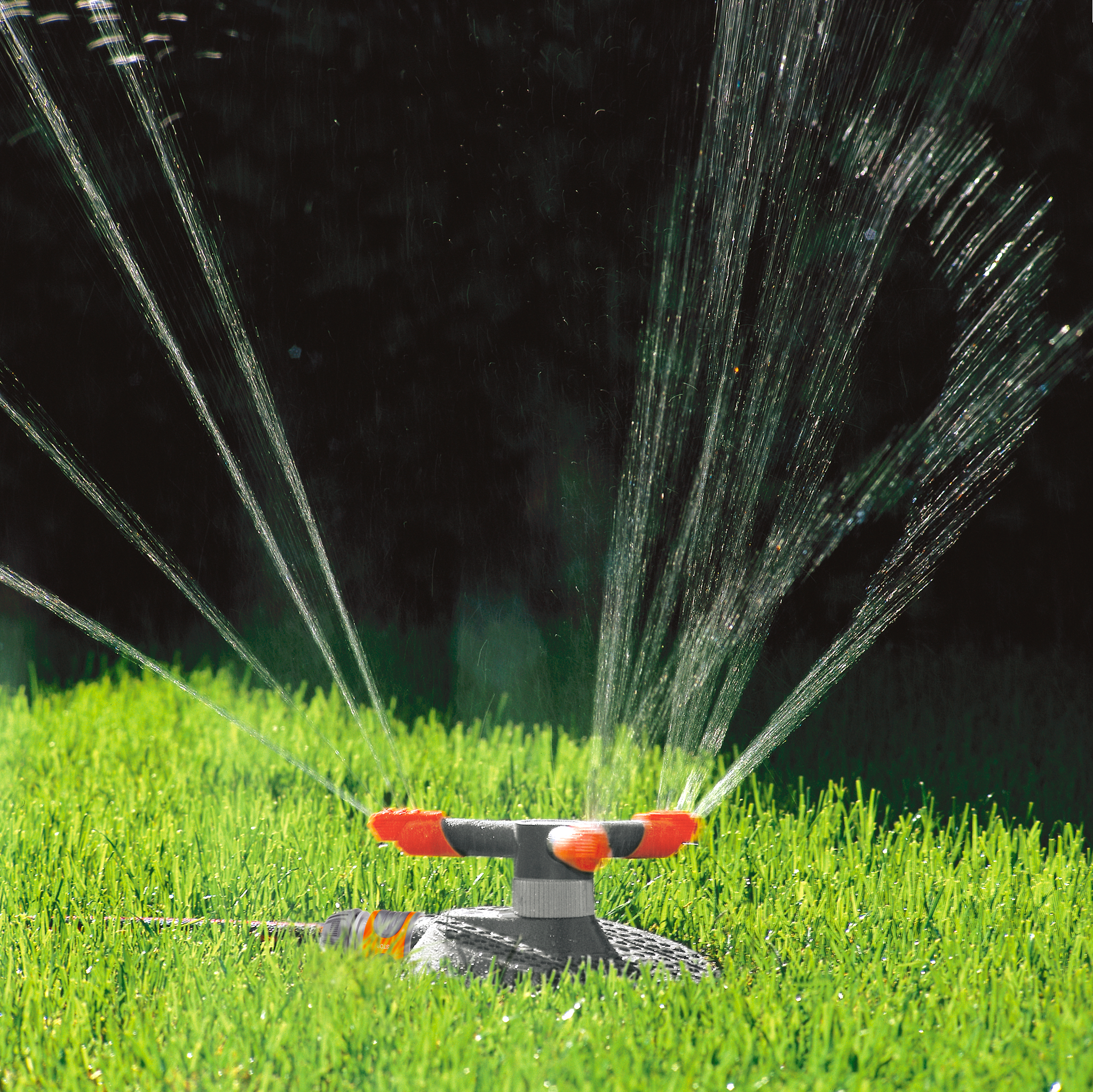 A garden sprinkler watering a lush green lawn with multiple streams of water.