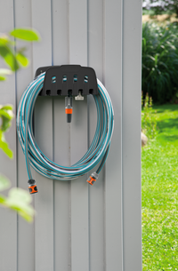 Gardena garden hose neatly coiled on a wall-mounted holder beside a green lawn., miniatuur 4