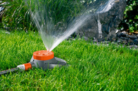 A garden sprinkler watering grass with a stone backdrop., miniatuur 4