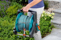A person carrying a Gardena hose reel in a garden setting., miniatuur 6