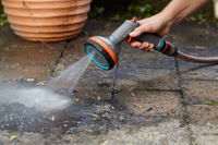 A person using a Gardena garden hose nozzle to clean a stone patio., miniatuur 6