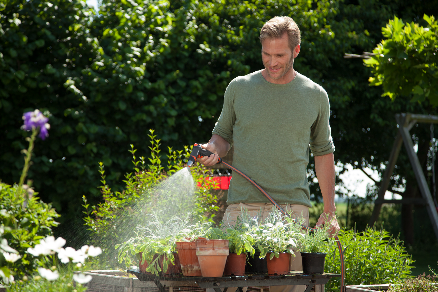 A person watering potted plants in a garden setting.