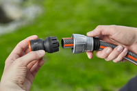 A person connecting a Gardena hose with a quick connector in a garden setting., miniatuur 5
