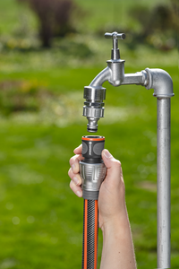 A person connecting a Gardena hose to an outdoor water tap in a garden., miniatuur 3