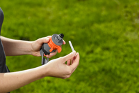 A person holding a Gardena hose nozzle and a small attachment in a garden setting., miniatuur 3