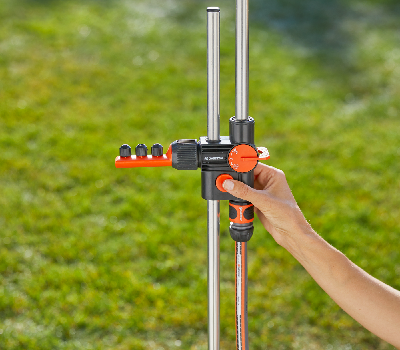 A person adjusting a Gardena water distribution system in a garden.