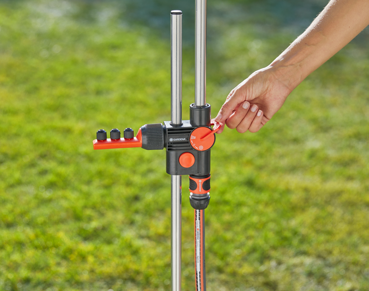 A person adjusting a Gardena water distributor in a garden setting.