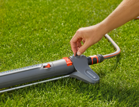 A person adjusting a Gardena garden sprinkler on a lawn., miniatuur 6
