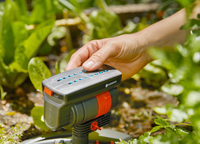 A person adjusting a Gardena irrigation control system in a garden., miniatuur 6