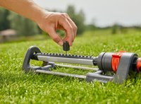 A person adjusting a Gardena garden sprinkler on a grassy lawn., miniatuur 3
