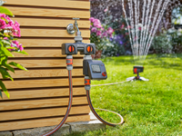A Gardena water control system connected to a garden tap, with a sprinkler in the background., miniatuur 5