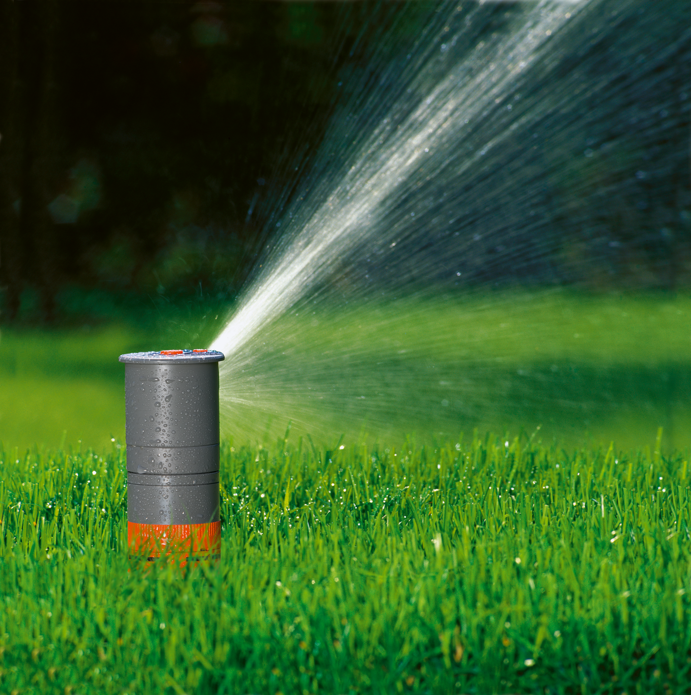 A Gardena pop-up sprinkler watering a lush green lawn.
