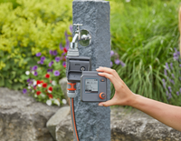 A person holding a digital garden water timer in front of a water tap, with a garden in the background., miniatuur 4