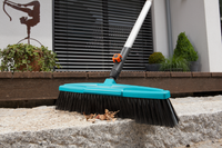 A Gardena broom sweeping leaves on a stone surface in a garden setting., miniatuur 5