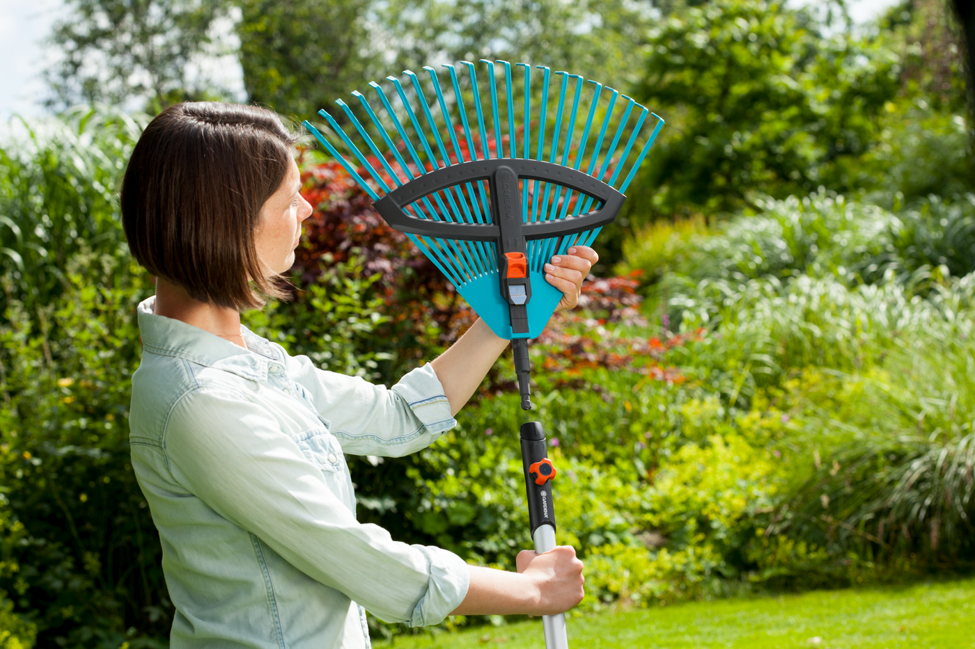 A person adjusting a garden rake in a lush garden setting.