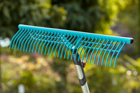 A close-up view of a garden rake with a long handle, set against a blurred outdoor background., miniatuur 4