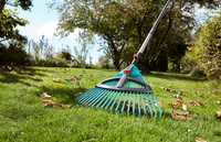 A Gardena rake being used to gather fallen leaves on a grassy lawn., miniatuur 4