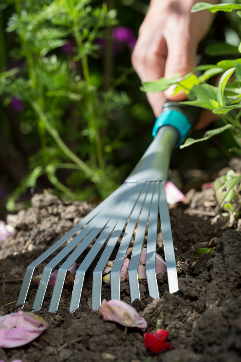 A person using a hand rake to tend to soil in a garden., afbeelding 2 Tuingereedschap
