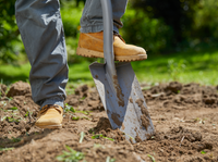 A person wearing work boots using a shovel to dig soil in a garden., miniatuur 2