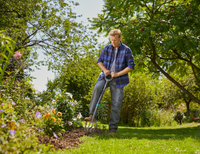 A person using a garden fork to tend to a flower bed in a lush garden., miniatuur 2