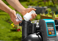 A person installing a filter into a Gardena water pump in a garden setting., miniatuur 2