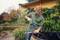 A person using a drill to assemble a garden water feature surrounded by plants., miniatuur 2