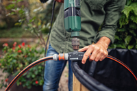 A person using a drill to attach Gardena garden hose connectors to a water barrel., miniatuur 3