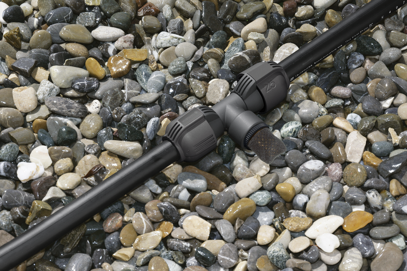 Gardena irrigation pipe connector on a bed of stones.