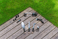 Gardening tools including a trowel, pruner, and spray nozzle arranged on a wooden deck next to grass., miniatuur 6