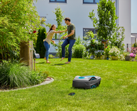 A robotic lawn mower operating in a garden while two people interact in the background., miniatuur 5
