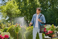 A person using a garden sprayer to water plants in a lush garden setting., miniatuur 3