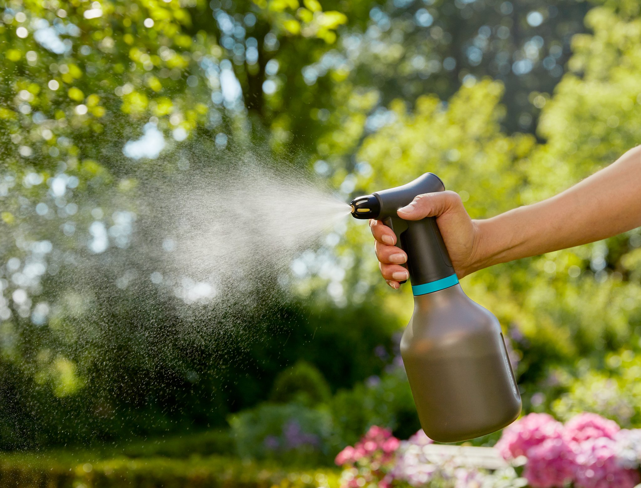 A person using a garden sprayer in a lush garden setting.