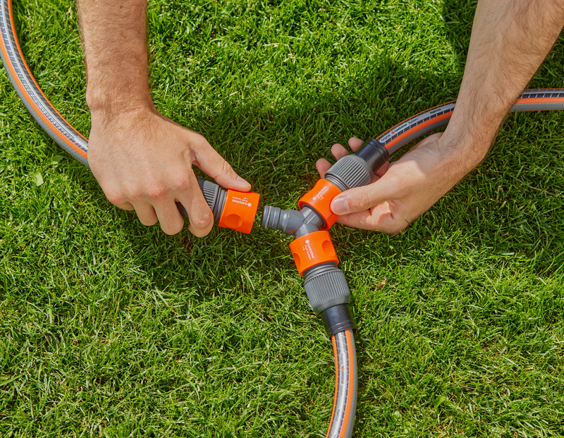 Hands connecting garden hoses using a three-way connector on grass., afbeelding 2 Tuinbenodigdheden