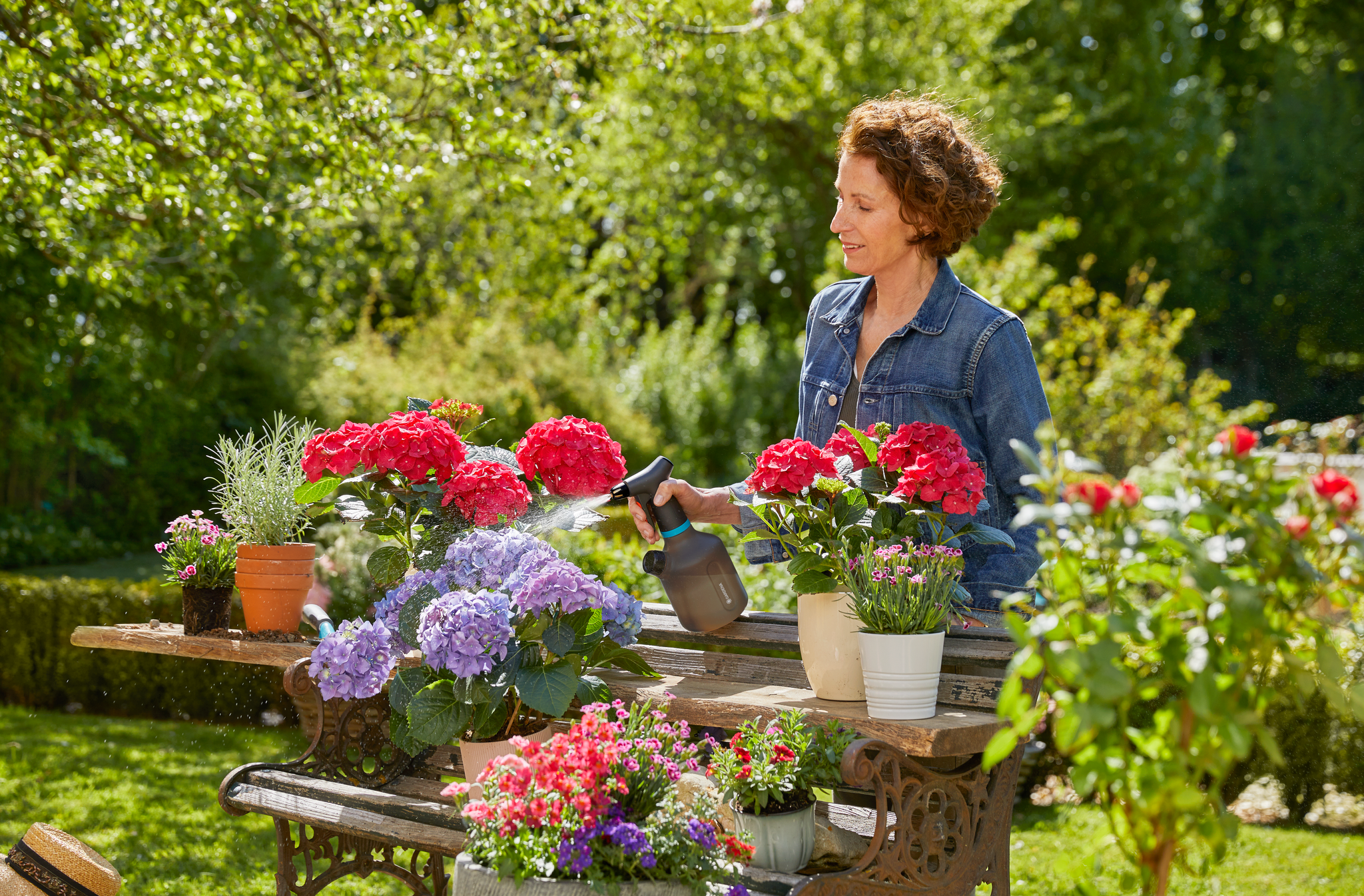 A person tending to potted flowers on a garden table.