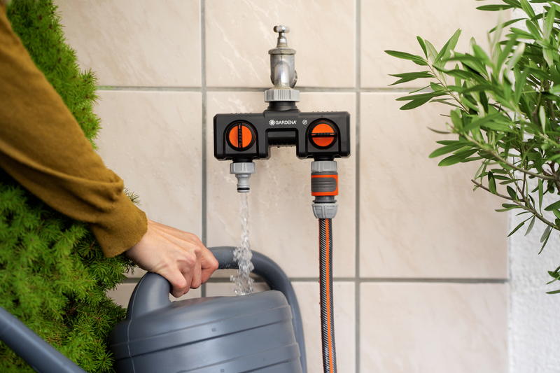 A person filling a watering can using a Gardena water tap splitter., detailaanzicht PVC Hulpstuk